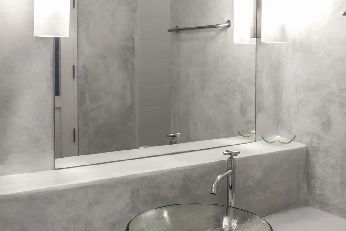 Salle de bain avec des murs et un comptoir en béton ciré gris